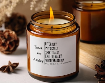 May include: A brown glass candle with a white label that reads "Thank You Ashley LITERALLY PHYSICALLY SPIRITUALLY EMOTIONALLY WHOLEHEARTEDLY Could Not Have Done It Without You".