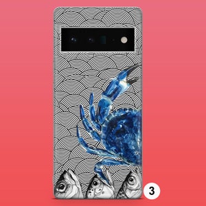 Op de afbeelding: Een telefoonhoesje met een zwart-wit patroon van overlappende cirkels. Een blauwe krab bevindt zich op het hoesje, met opgeheven scharen. Drie vissen bevinden zich aan de onderkant van het hoesje.
