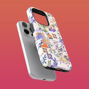 Peut inclure: Une coque de téléphone iPhone blanche avec un motif floral coloré. La coque présente un motif floral bleu, orange et vert sur fond blanc. La coque est présentée sur un iPhone blanc.