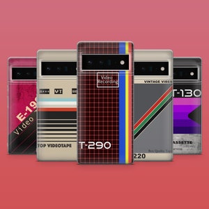 May include: Five different phone cases with a retro VHS tape design. The cases feature different colors and designs, including red, black, white, gray, and purple. The text on the cases includes "Video Recording", "Vintage Vibes", "T-290", "E-19", and "T-130".