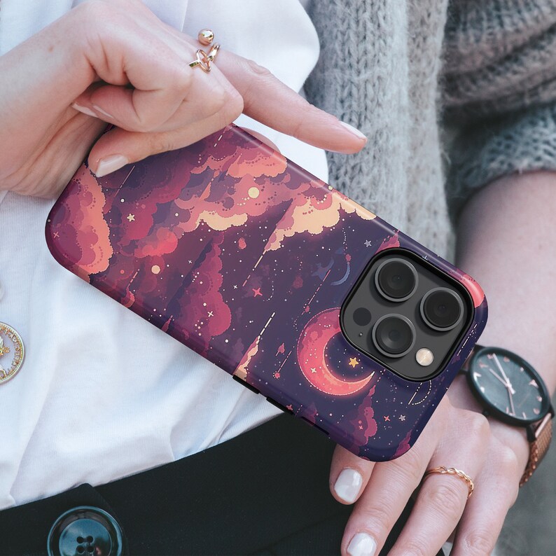 May include: A purple phone case with a colourful design of clouds, stars, and a crescent moon. The case has a camera lens cutout with three black circles.