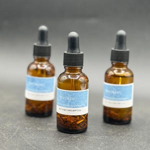 May include: Three brown glass bottles with black droppers. Each bottle has a light blue label with the word "INVOKING" and the website "mysticmanconjure.com". The bottles contain a brown liquid and plant material. The text "NOT FOR CONSUMPTION" is also on the label.