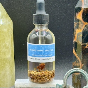 May include: A clear glass bottle with a black dropper top filled with a light brown liquid and herbs. The label reads "Money Draw - Fast Cash" and "mysticmanconjure.com". The bottle is 2 oz and is not for consumption.