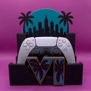 Könnte beinhalten: Ein schwarzer Gaming-Controller-Ständer mit einem türkisfarbenen, kreisförmigen Hintergrund, der eine schwarze Stadtsilhouette und Palmen zeigt. Die Vorderseite des Ständers zeigt die römische Ziffer VI in Blau mit schwarzen Palmen.