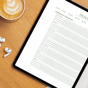 May include: A digital tablet displaying a health tracker with sections for supplements and medications. The tracker includes daily entries for January through May, with spaces for tracking morning, afternoon, and evening routines. A cup of coffee and earbuds are on the wooden surface.