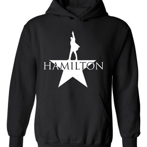 May include: Black hooded sweatshirt with a white silhouette of a person standing on a star with the word "HAMILTON" printed below.