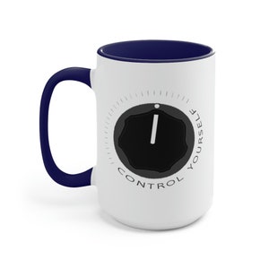 May include: White ceramic coffee mug with a blue rim and handle. The mug features a black and white graphic of a knob with the text "CONTROL YOURSELF" around it.