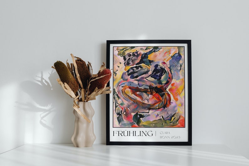 May include: A framed abstract art print featuring a colourful, swirling design in shades of pink, yellow, blue, and red. The print is titled "FR&Uuml;HLING" with the artist's name and date "CLARA | BONN 2021" below the title.