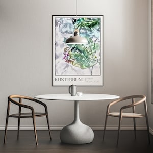 May include: A white table with a round top and a grey base sits in a room with two wooden chairs. A white pendant light hangs above the table. A framed poster with a colourful abstract design hangs on the wall behind the table. The poster has the text "Kunterbunt | Philipp Joan 2023".