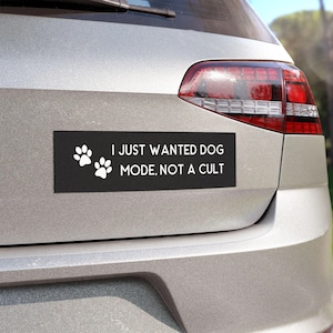 May include: A black and white car bumper sticker with two white paw prints and the text "I JUST WANTED DOG MODE, NOT A CULT."