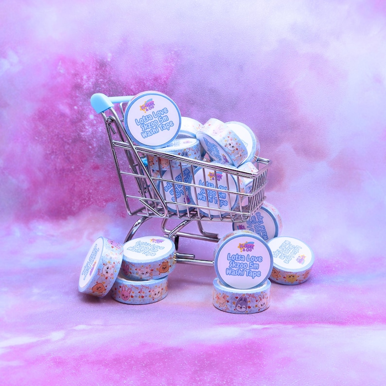 May include: A miniature shopping cart filled with rolls of washi tape. The tape rolls are light blue with a repeating pattern of cartoon characters. Each roll has a label that reads "Lotsa Love Skzoo 5m Washi Tape."