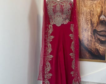 May include: A deep magenta jumpsuit featuring a sweetheart neckline bodice with intricate silver embroidery and beadwork. The garment includes wide-leg trousers with matching silver floral embroidery along the sides and a sheer magenta cape overlay.