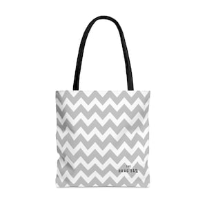 May include: A gray and white chevron patterned tote bag with black handles. The bag has the text "THE BRAG BAG" printed on the front.