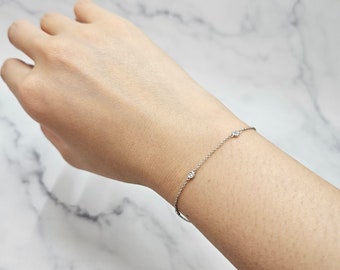 May include: A delicate silver chain bracelet with three small, clear gemstones.
