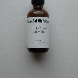 May include: A brown glass bottle with a black cap, labeled "Colloidal Alchemist Colloidal Silver 20 PPM 2 FL OZ. (59.14 ML)"