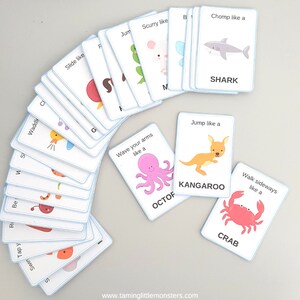May include: A set of colorful flashcards with animal illustrations and action words. Each card features a different animal, such as a shark, kangaroo, crab, and octopus, and a corresponding action verb, such as "chomp like a", "jump like a", "walk sideways like a", and "wave your arms like a".
