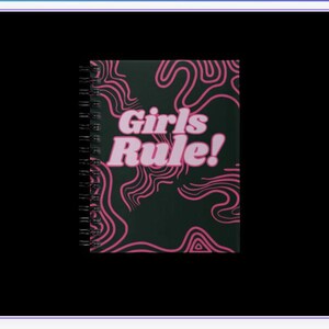 May include: A black spiral notebook with a pink and black abstract design. The text "Girls Rule!" is printed in pink on the front cover.