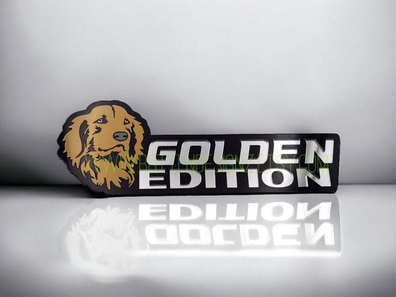 May include: A black and silver license plate frame with a golden retriever dog illustration and the text "GOLDEN EDITION".