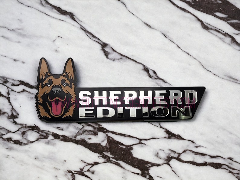 以下が含まれることがあります： ドイツシェパードの犬の頭と「SHEPHERD EDITION」の文字が書かれた黒と銀の金属製のエンブレムです。