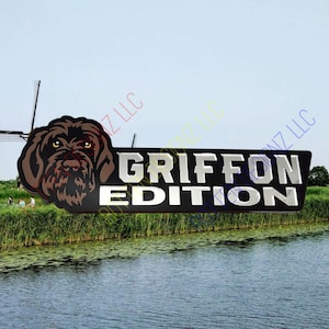 May include: A black and silver sign with the text "GRIFFON EDITION" in silver letters. A brown dog's head is on the left side of the sign.