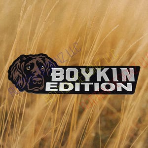 May include: A black and silver metal emblem with a brown and black dog head illustration. The text "Boykin Edition" is printed in silver on the emblem.