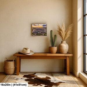 a wooden bench with a cowboy hat and a potted plant on top, along with a painting of a stadium in the background.