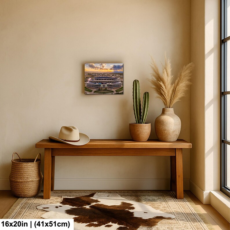 a wooden bench with a cowboy hat and a potted plant on top, along with a painting of a stadium in the background.