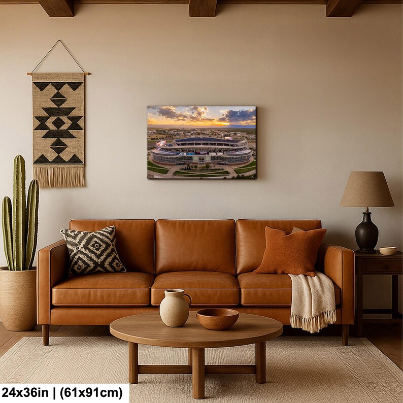 a cozy living room with a brown leather sofa, a wooden coffee table, and a wall hanging featuring a large stadium.