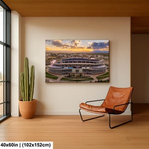 a large stadium with a beautiful sunset in the background, and a brown leather chair is placed next to a potted plant in the corner of the room.
