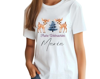 Könnte beinhalten: Weißes T-Shirt mit einem weihnachtlichen Design mit zwei Cartoon-Rehen und einem blauen Weihnachtsbaum. Der Text "Frohe Weihnachten Maria" ist unter dem Design gedruckt.