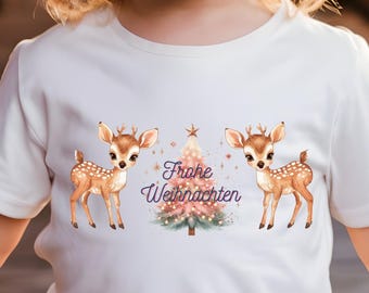Könnte beinhalten: Weißes T-Shirt für Kleinkinder mit einem Weihnachtsbaum und zwei Rehen. Der Baum ist rosa und grün mit goldenen Lichtern. Der Text "Frohe Weihnachten" ist auf das Shirt gedruckt.