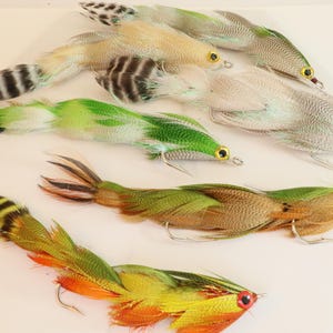 May include: Six different fly fishing lures with feathers and various colors, including green, brown, white, and yellow.
