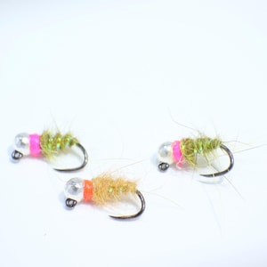 May include: Three fly fishing lures with pink and orange accents. The lures are tied with green, brown, and white fibers.