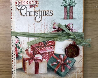 May include: A Christmas-themed journal with illustrations of wrapped gifts and ribbons. The cover displays the words "Merry Christmas." A green ribbon wraps around the journal, and a wax seal adds a vintage touch. The journal's edge is decorated with lace.