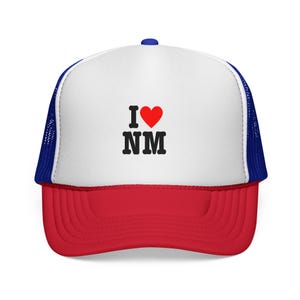 May include: A red, white, and blue trucker hat with the text "I ♥ NM" in black and red. The hat features a red brim, a white front panel, and a blue mesh back. A small blue button is on top.