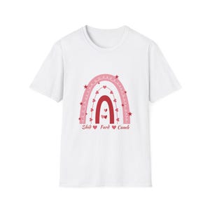 May include: White t-shirt featuring a pink and red rainbow design with hearts and stars. The text "Shid Fard Cumb" is printed below the rainbow. A casual, everyday wear tee.