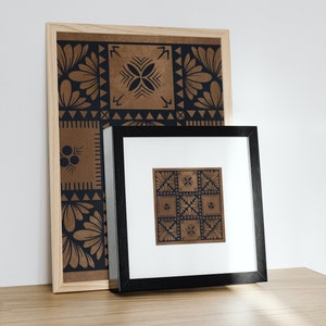 May include: Two framed prints with geometric patterns in black and brown. The larger print is in a light wood frame and the smaller print is in a black frame.