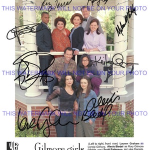 May include: A black and white photo of the cast of the Gilmore Girls television show. The cast members are standing on a porch and are all smiling. The photo is signed by the cast members. The text "Gilmore Girls" is printed below the photo.