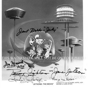 May include: Black and white photo of the cast of the animated television series The Jetsons. The cast members are standing in front of a futuristic cityscape. The photo is signed by the cast members, including Don Messick, Jane  Jetson, and Judy.