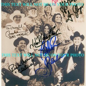 May include: A black and white photo of a group of people, including a dog, with their autographs. The text "THIS TEXT WILL NOT BE ON YOUR PHOTO" appears twice on the image.