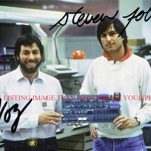 May include: A black and white photo of two men, one holding a circuit board. The man on the left is smiling and has a beard. The man on the right is looking at the camera. The text "Steven Jobs" is written in black ink above the men's heads. The text "Woz" is written in black ink below the men's hands.