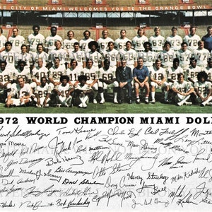 May include: A black and white photo of the 1972 Miami Dolphins World Champion team. The team is standing in a line on a green field. The players are wearing their uniforms and helmets. The team is holding a trophy. The photo is signed by all of the players. The text "THE 1972 WORLD CHAMPION MIAMI DOLPHINS" is printed at the bottom of the photo.