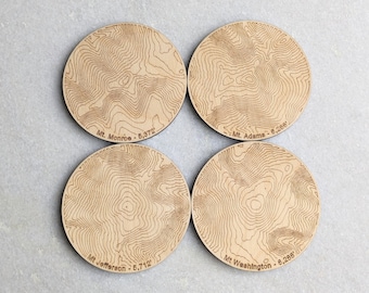 May include: Set of four wooden coasters featuring topographic maps of four mountains: Mt. Monroe, Mt. Adams, Mt. Washington, and Mt. Jefferson. Each coaster includes the mountain's name and elevation in feet.