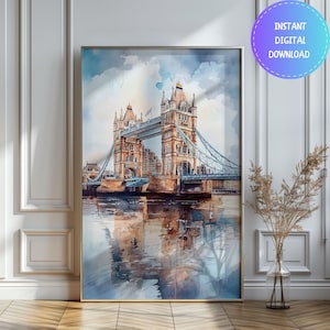 May include: Watercolor painting of the Tower Bridge in London, framed in a gold-colored border. The artwork depicts the bridge with its iconic towers and blue suspension cables, reflected in the water below. The sky is a mix of blue and white, with the text "INSTANT DIGITAL DOWNLOAD".