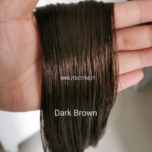May include: Close-up of a bundle of dark brown human hair extensions. The hair is smooth and silky, with a slight sheen. The text "Dark Brown" is visible at the bottom of the image.