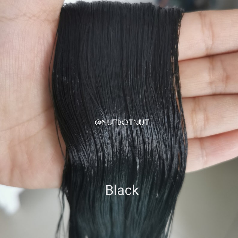 May include: Close-up of black embroidery floss, showing the individual strands of thread. The text "Black" is visible below the floss.