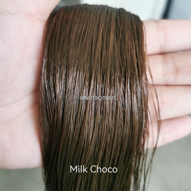 May include: A close-up of a strand of brown hair, showing the texture and color. The hair is labeled "Milk Choco".