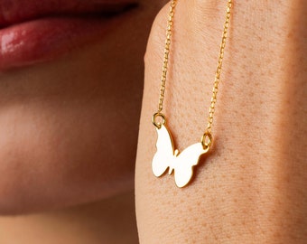 May include: A gold chain necklace with a delicate butterfly pendant. The butterfly is a simple, flat design with a smooth, polished finish.