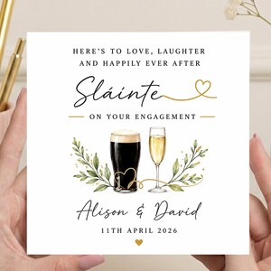 May include: A square engagement greeting card with white background featuring the text HERE'S TO LOVE, LAUGHTER AND HAPPILY EVER AFTER, Sláinte, ON YOUR ENGAGEMENT, Alison & David, and 11TH APRIL 2026. Includes a dark stout beer and champagne flute.