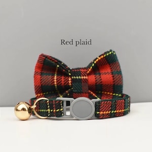 Puede incluir: Collar para gato de cuadros rojos con una pajarita a juego y una campanilla dorada.